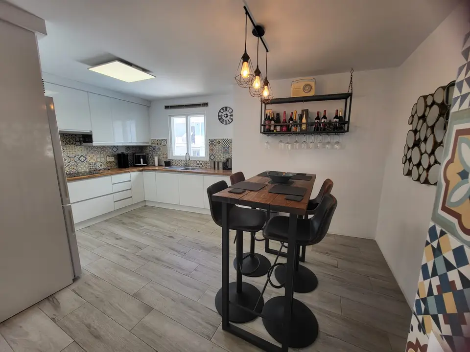 Een gerenoveerde keuken met een houten bar en hanglampen
